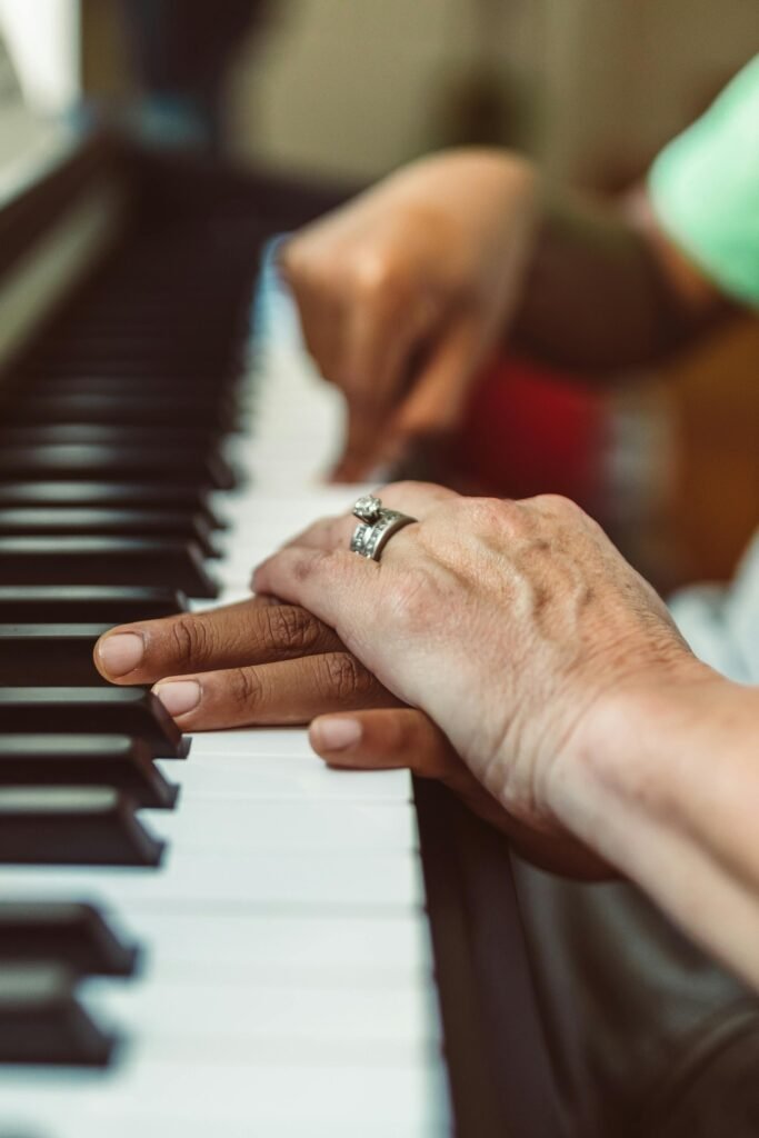 Hands playing piano keys in detail with a ring, showcasing music learning and connection.